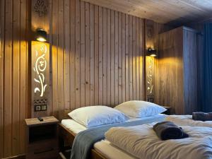 two beds in a room with wood paneled walls at Felągówka in Murzasichle