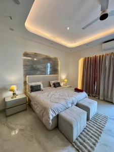 a bedroom with a large bed with two ottomans sidx sidx sidx sidx at Sky High Nest Noida in Ghaziabad