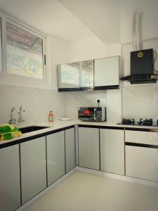 a kitchen with white cabinets and a sink at Marari Jose Villas in Mararikulam