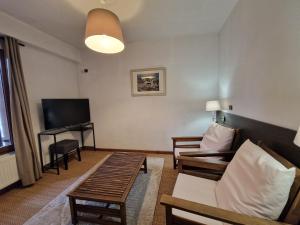 a living room with a couch and a television at Le Relais Des Dix Crus - Logis Hôtel in Corcelles-en-Beaujolais