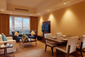 a living room with a dining table and a television at Jannah Burj Al Sarab in Abu Dhabi