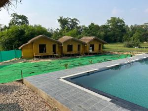 a group of huts with a swimming pool in front at Bamboo Life in Dera Gopipur