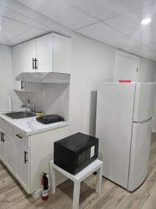 a kitchen with white cabinets and a tv on a stool at 2 Bedroom Suite in Transcona in Winnipeg