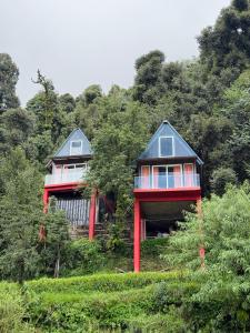 two houses on a hill with trees in the background at The Mystic Loft in Dharamshala