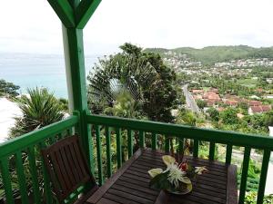 a wooden bench on a balcony with a view of the ocean at Les Gites Josiane in Les Trois-Îlets