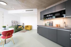 a kitchen with black cabinets and a living room at Domeq FREE Parking, Gym, Co-working and Terrace in Komárov