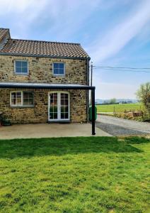 a stone house with a green lawn in front of it at La petite maison de Terre de Partage in Ohey