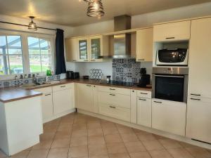 a kitchen with white cabinets and white appliances at La petite maison de Terre de Partage in Ohey