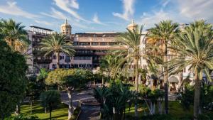 a building with palm trees in front of it at Santa Catalina, a Royal Hideaway Hotel - Gran Lujo in Las Palmas de Gran Canaria