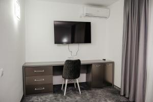 a desk with a chair and a television on a wall at Motel Moara Veche in Săcălăşeni