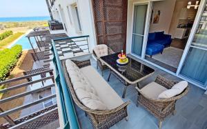 a balcony with a couch and chairs and a table at Thalassa Beach Resort - 107 in Vokolidha
