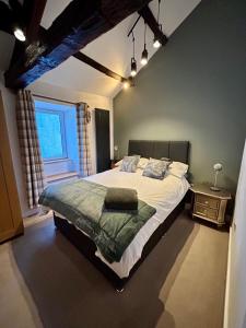 a bedroom with a large bed with a green blanket at Bakers Cottage in Cockermouth