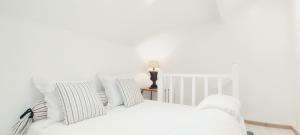 a white bedroom with a white bed with striped pillows at PARIS AUTHENTIC HOUSE Métro 7 Pierre et Marie Curie in Paris