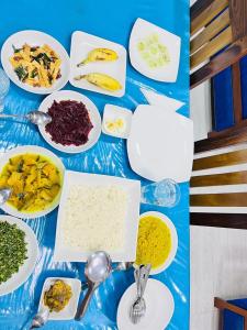 a blue table with plates of food and spoons at Ohiya Alpine River Lodge in Ohiya