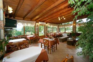 ein Restaurant mit Tischen und Stühlen in einem Gebäude in der Unterkunft Orama Hotel - Serene Lake Plastira Retreat with Stunning Views in Kryonérion