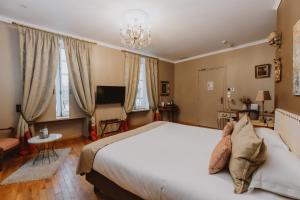 a bedroom with a large bed and a chandelier at Domaine de Larchey & son restaurant - Bordeaux Sud in Saint-Médard-dʼEyrans