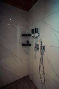 a shower in a bathroom with white marble walls at Kihnuvillas - Männirahu in Linaküla