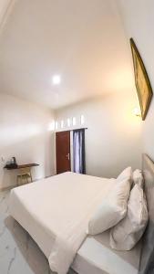 a bedroom with a large white bed in a room at Arka Homestay Pesagi in Karangasem