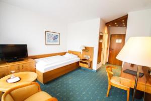 a hotel room with a bed and a television at Pension Augsburg Ost in Augsburg