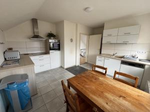 a kitchen with white cabinets and a wooden table at Pension Augsburg Ost in Augsburg