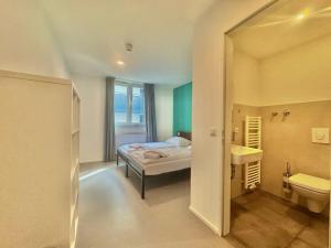 a bedroom with a bed and a bathroom with a sink at Pension Augsburg Ost in Augsburg