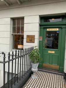 a green door to a store with a potted plant in front at Four Stars Hotel in London
