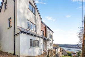 an exterior view of a white house with a river in the background at 4 Bed in Goodwick oc-s34887 in Goodwick