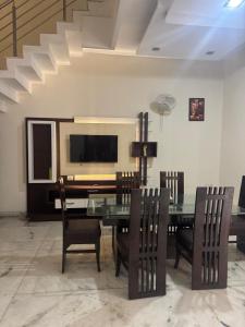 a dining room with a glass table and chairs at Auranest Stays Duplex Home in Ludhiana