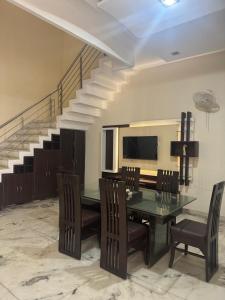 a dining room with a table and chairs and a staircase at Auranest Stays Duplex Home in Ludhiana