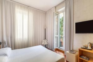 a bedroom with a white bed and a large window at Hotel Sanpi Milano in Milan