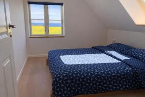 a bedroom with a bed with a blue comforter and a window at Solhjem Bornholm - Top Rated Sea View Stay in Gudhjem