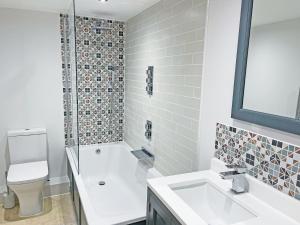 a white bathroom with a toilet and a sink at Headlands Hideaway in Coverack