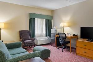a hotel room with chairs and a tv and a desk at All Seasons Inn & Suites Smithfield Providence in Smithfield