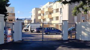 a gate with cars parked in front of a building at Studio avec parking privé - Proche écoles & hôpital - Valence in Valence