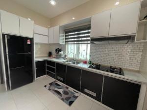 a kitchen with white cabinets and a black refrigerator at Afiq's Homestay, Manjung in Seri Manjung +15 photos