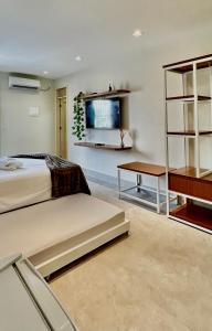 a bedroom with two beds and a table and a shelf at Seridó Acomodações in Caicó