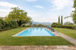 a swimming pool in a yard with chairs and trees at Villa Beltramonto by MMega in Castiglioncello del Trinoro