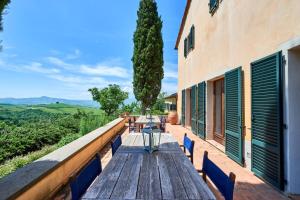 a wooden table and chairs on the balcony of a building at Villa Beltramonto by MMega in Castiglioncello del Trinoro