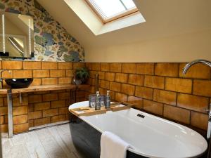 a bathroom with a large tub and a skylight at No33 THORNHAM BOUTIQUE SUITES in Thornham +44 photos