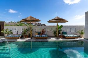a woman sitting on a chair next to a swimming pool at Villa Riad- וילה ריאד מתחם נופש יוקרתי in Migdal