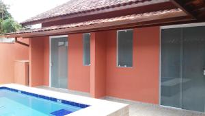 a house with a swimming pool in front of it at Suite Recanto Cheiro Verde in Caraguatatuba