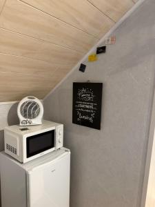 a microwave on top of a refrigerator with a sign at HOME SÉRÉNITÉ in Hazelbourg