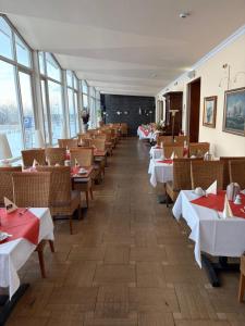 a dining room with tables and chairs and windows at Hotel Stolteraa in Warnemünde