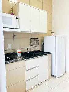 a kitchen with white cabinets and a white refrigerator at Ap3 - Studio Confortável e Tranquilo in Guaíra