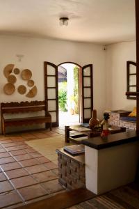 a living room with a table and a room with logs on the wall at Pousada Recanto da Ladeira in Paraty