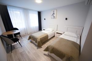 a bedroom with two beds and a desk and a table at Dzūkija Hotel in Alytus