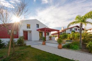 a white house with a red door and palm trees at SUNSET Keyweek Villa ocean view and private pool in Bidart