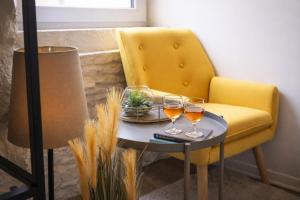 a table with two glasses of wine on a yellow chair at Little Urban Home in Trieste