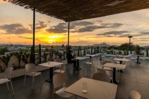 a person sitting at tables on a roof with a sunset at Santonita Hotel & Tours in Ninh Hải +39 photos