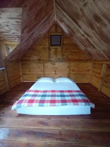 a bed in the attic of a wooden cabin at JE House in Ambarita
